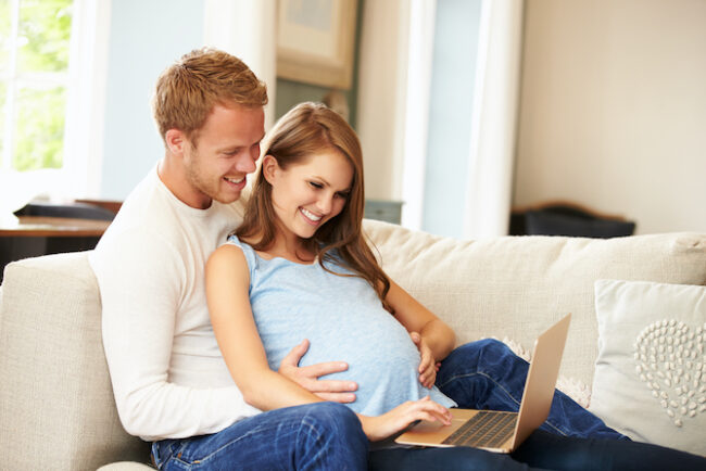 Couple With Pregnant Woman Using Laptop Computer Together
