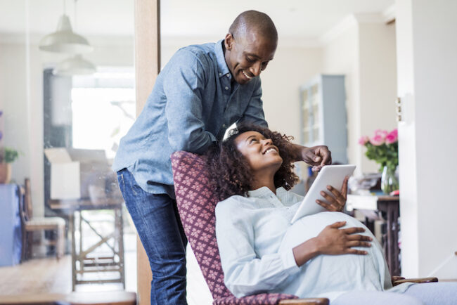 Happy pregnant woman looking at man in home