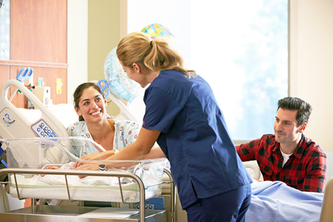 Family And Nurse With New Born Baby In Post Natal