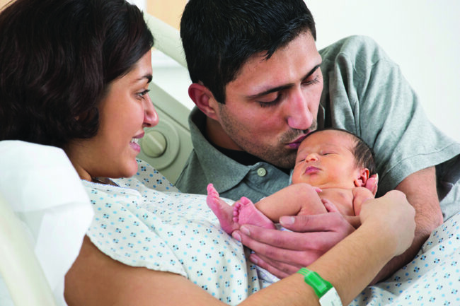 Couple admiring newborn baby in hospital